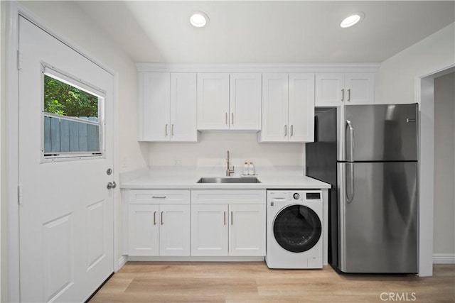 laundry room with washer / clothes dryer, sink, and light wood-type flooring