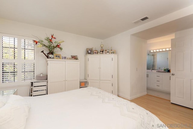 bedroom with ensuite bathroom, sink, and light wood-type flooring