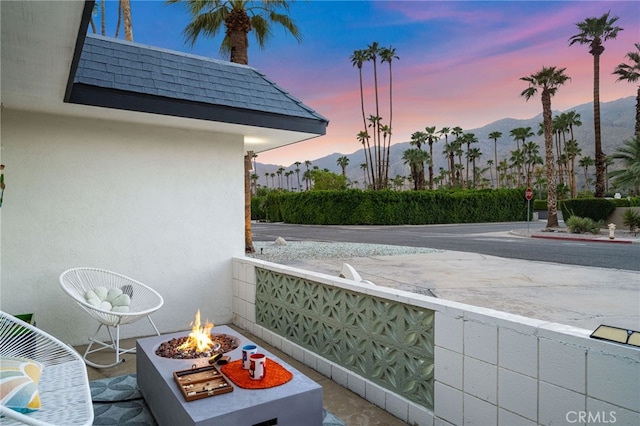 balcony at dusk featuring a mountain view and a fire pit