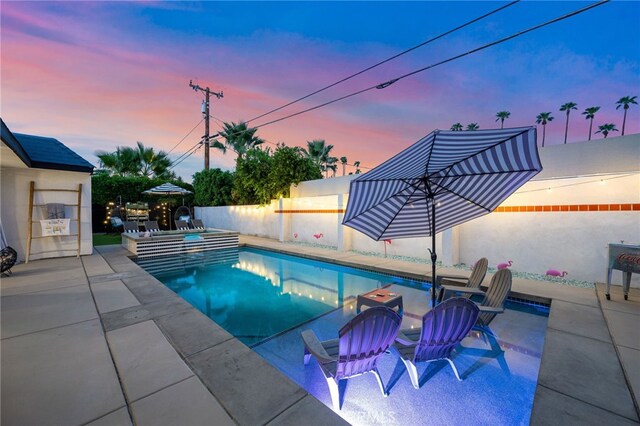 pool at dusk with a patio area