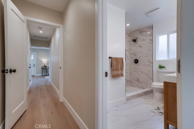 bathroom with vanity, toilet, and a tile shower