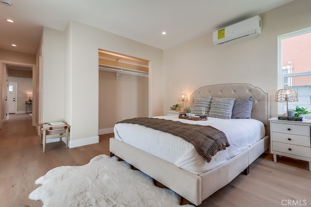 bedroom with light hardwood / wood-style flooring, a wall unit AC, and a closet