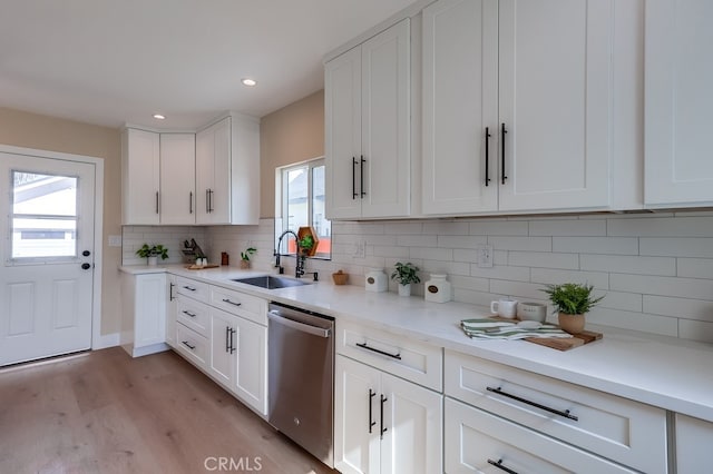 kitchen featuring sink, white cabinetry, backsplash, light hardwood / wood-style floors, and stainless steel dishwasher