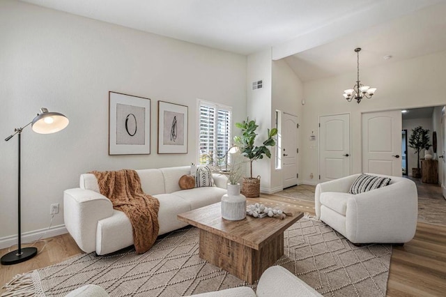 living room with beamed ceiling, high vaulted ceiling, a chandelier, and light wood-type flooring