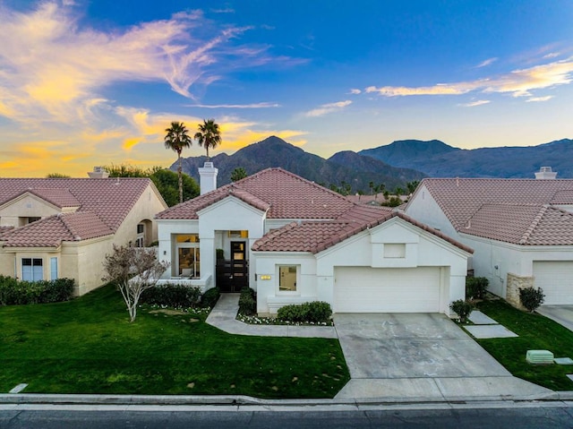 mediterranean / spanish home featuring a mountain view, a garage, and a lawn