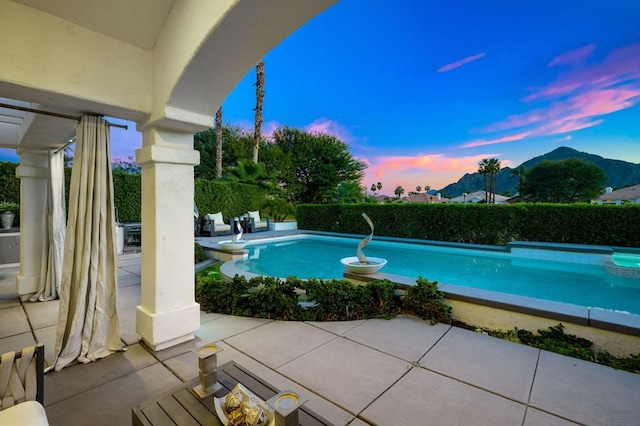 pool at dusk with a mountain view and a patio area