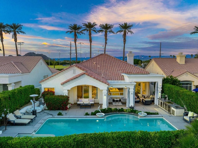 back house at dusk featuring an outdoor living space and a patio