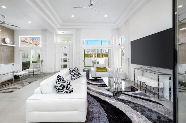 living room with a high ceiling, crown molding, and ceiling fan