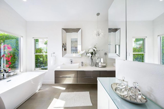 bathroom featuring vanity, a notable chandelier, and a bathtub