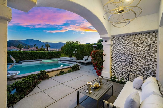 exterior space with an in ground hot tub, a mountain view, ceiling fan, and a patio area