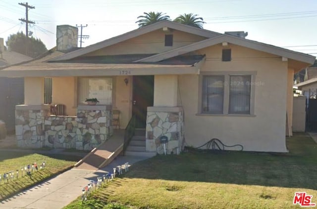 bungalow featuring covered porch and a front lawn