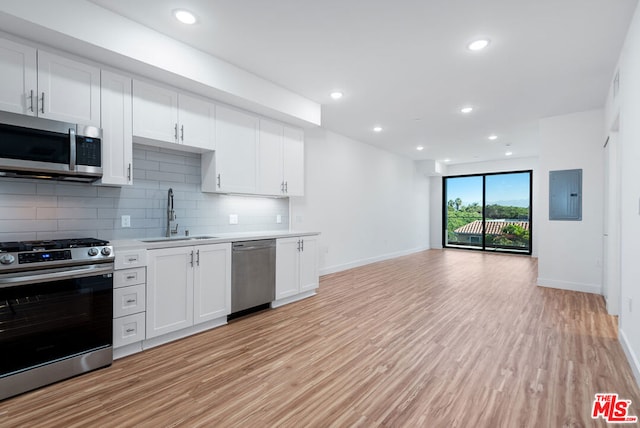 kitchen featuring sink, appliances with stainless steel finishes, white cabinetry, electric panel, and light wood-type flooring