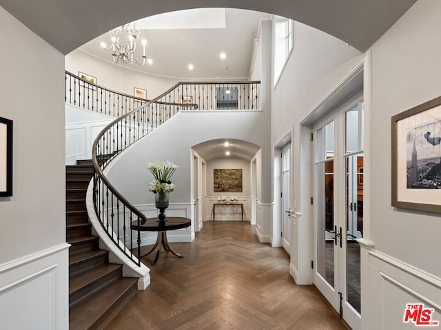 entrance foyer featuring a notable chandelier, parquet flooring, french doors, and a high ceiling