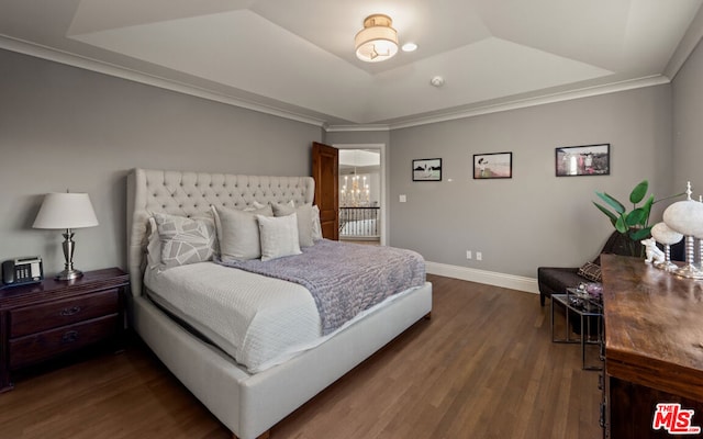 bedroom featuring a raised ceiling, ornamental molding, and dark wood-type flooring