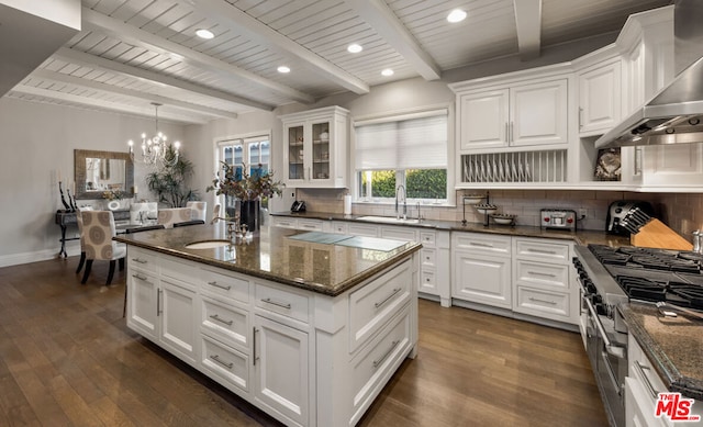 kitchen with white cabinetry, wall chimney range hood, backsplash, and range with two ovens