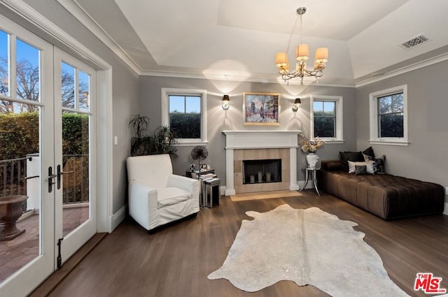 living room featuring a notable chandelier, a tile fireplace, dark hardwood / wood-style floors, and a raised ceiling