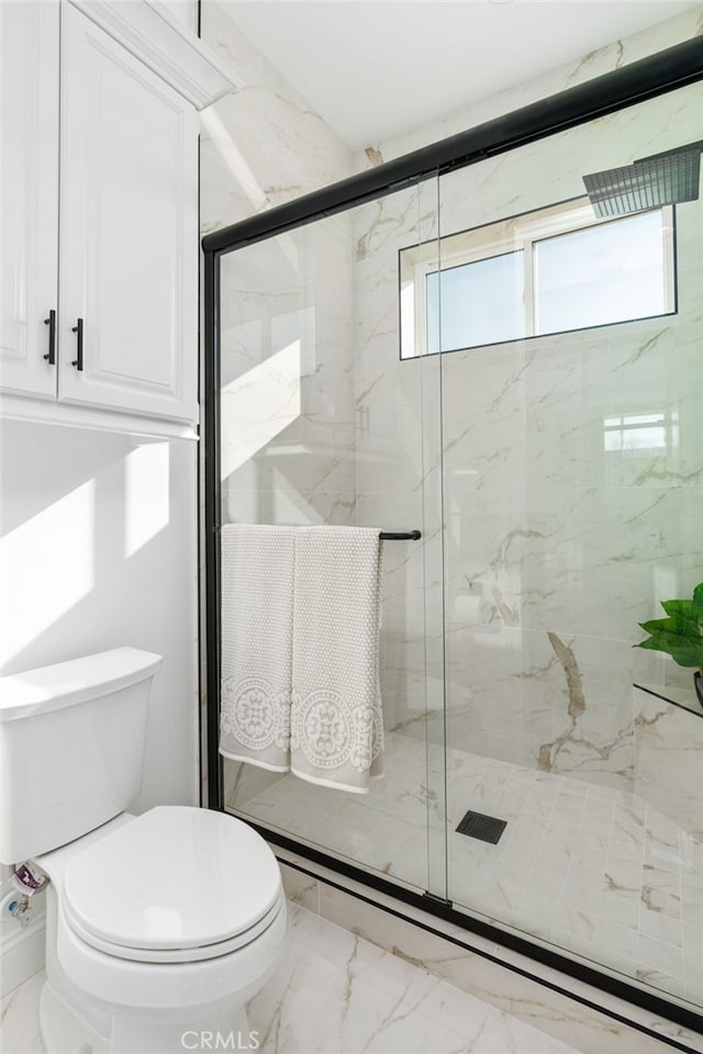 bathroom featuring toilet, a shower with shower door, and a wealth of natural light