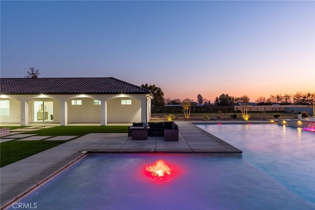 pool at dusk featuring a patio