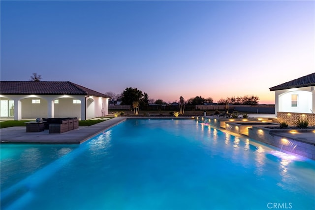 pool at dusk featuring outdoor lounge area and a patio