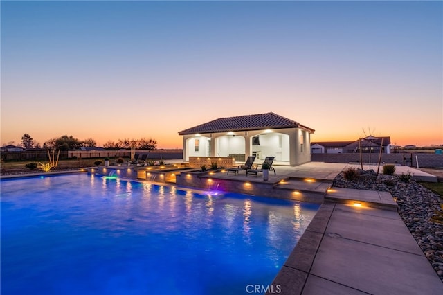 pool at dusk with a patio and an outbuilding