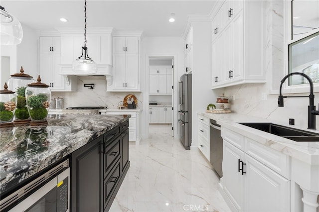 kitchen with pendant lighting, sink, white cabinets, light stone counters, and stainless steel appliances