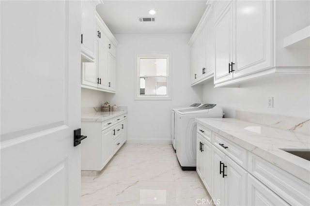 clothes washing area featuring cabinets and washing machine and dryer