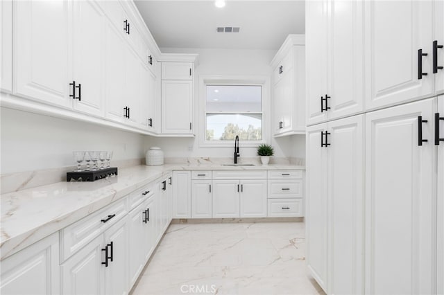 kitchen featuring white cabinetry, light stone countertops, and sink