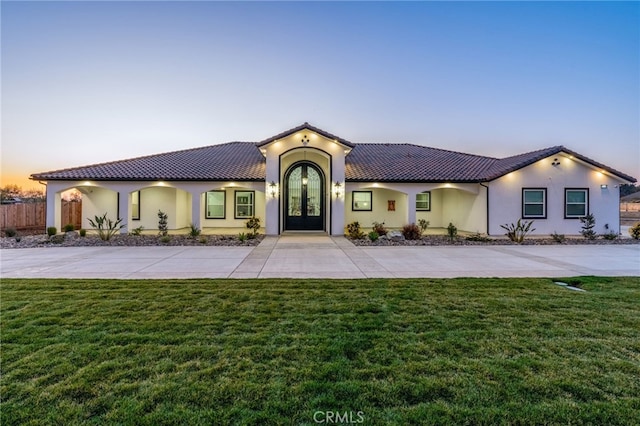 mediterranean / spanish-style house with french doors and a yard