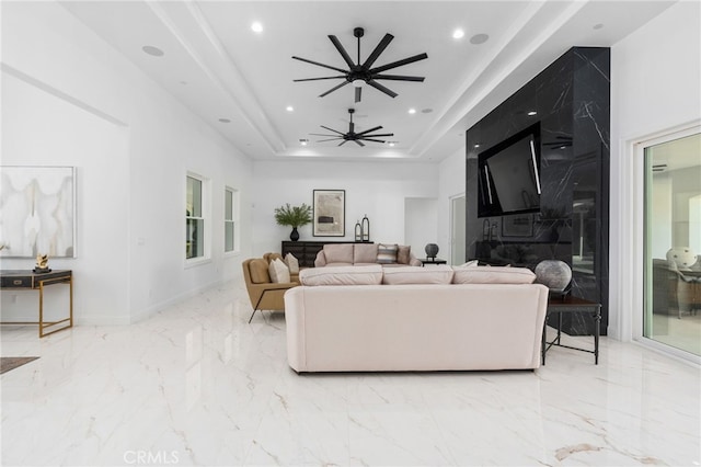 living room with a raised ceiling and ceiling fan