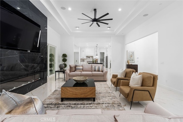 living room with a raised ceiling and ceiling fan