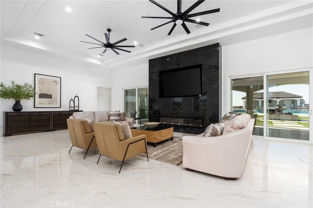 living room with ceiling fan and a raised ceiling