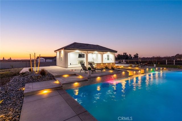 pool at dusk with an outbuilding and a patio area