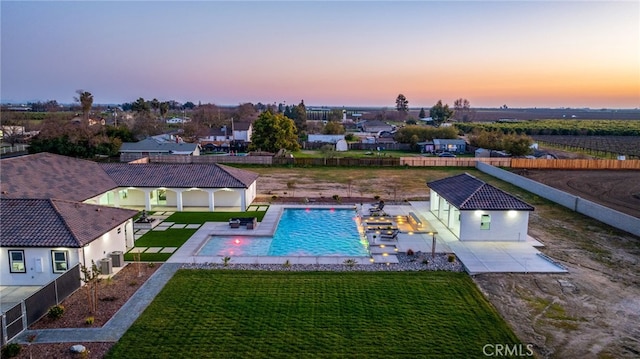 pool at dusk with an outbuilding, a yard, and a patio area