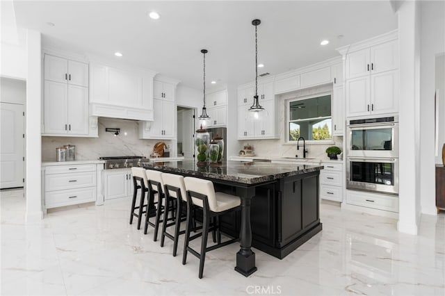 kitchen featuring stainless steel appliances, white cabinetry, a center island, and dark stone countertops