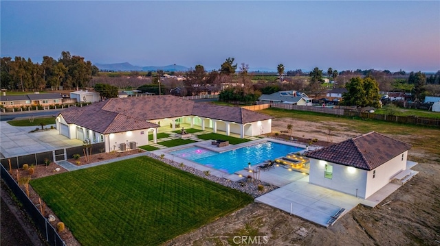 pool at dusk featuring a yard and a patio