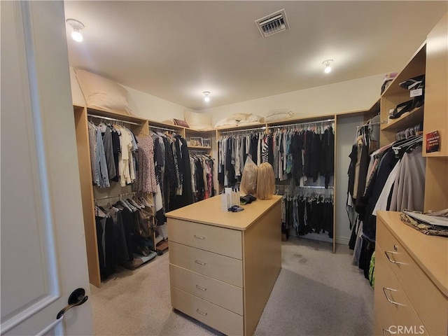 walk in closet with light carpet