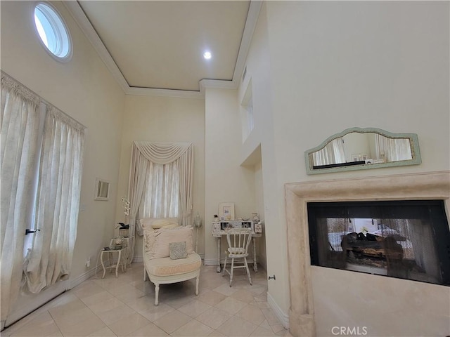 sitting room with baseboards, ornamental molding, a high ceiling, and tile patterned floors
