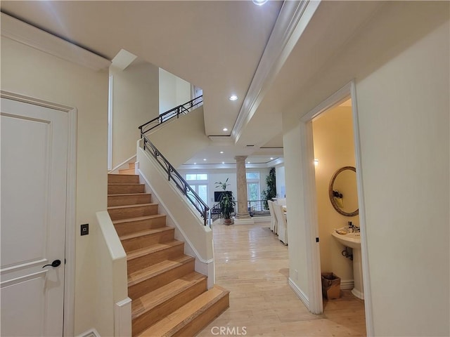 stairway featuring hardwood / wood-style floors, ornamental molding, and decorative columns