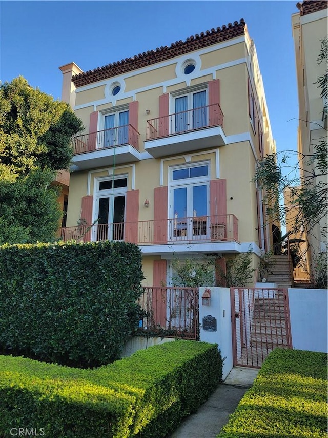 mediterranean / spanish-style home with fence, stucco siding, and a gate