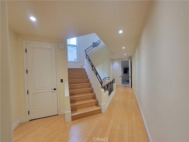 stairway with recessed lighting, baseboards, and wood finished floors
