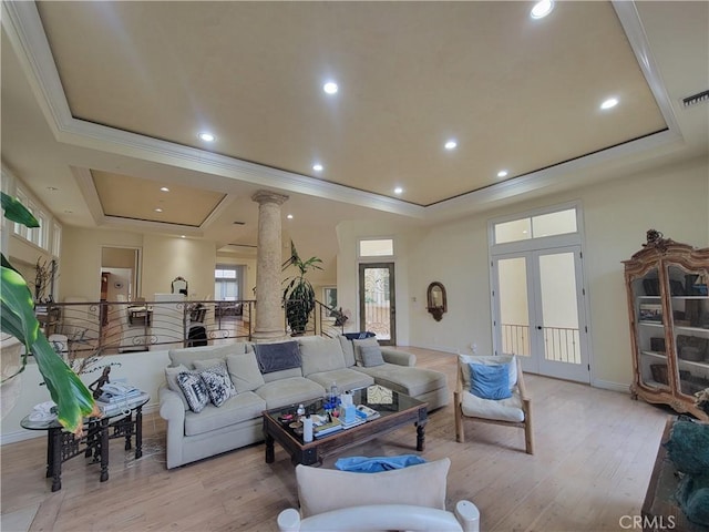 living room with light hardwood / wood-style floors, a tray ceiling, decorative columns, and french doors