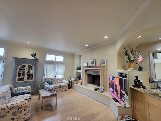 living room featuring light wood-type flooring, crown molding, and a fireplace with raised hearth