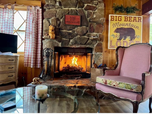 sitting room featuring a fireplace, wood-type flooring, and wooden walls