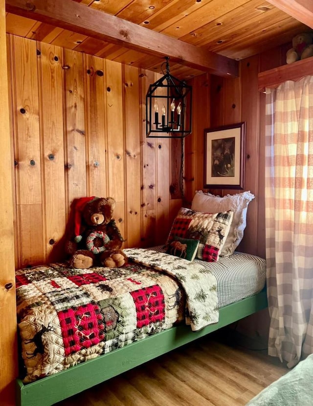 bedroom with wood walls, beamed ceiling, wood-type flooring, a notable chandelier, and wooden ceiling