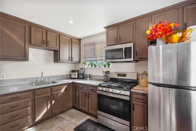 kitchen featuring light stone counters, appliances with stainless steel finishes, sink, and light tile patterned floors