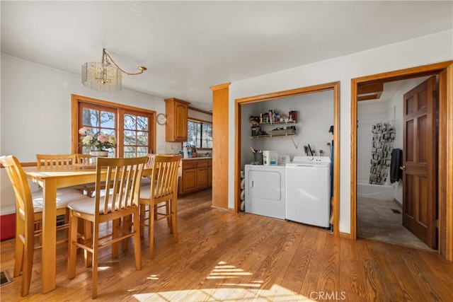 dining area with an inviting chandelier, light hardwood / wood-style floors, and independent washer and dryer