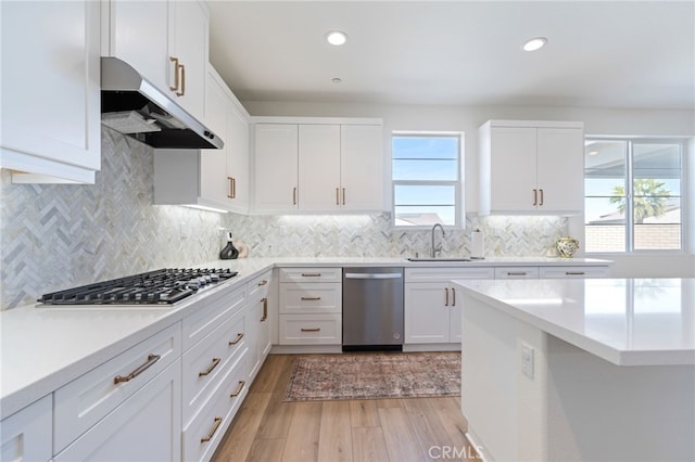 kitchen with sink, white cabinetry, light wood-type flooring, stainless steel appliances, and decorative backsplash