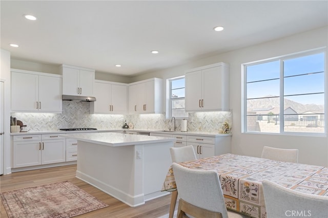 kitchen featuring white cabinetry, sink, a center island, gas cooktop, and light wood-type flooring