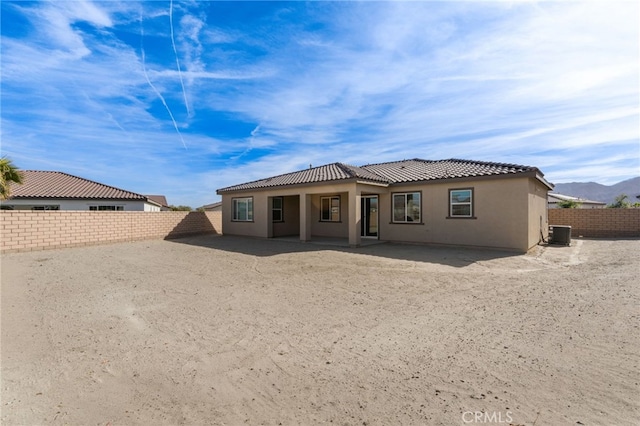 back of property with cooling unit, a mountain view, and a patio area