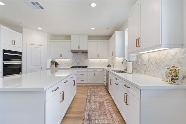 kitchen with sink, stainless steel dishwasher, black double oven, light hardwood / wood-style floors, and white cabinets